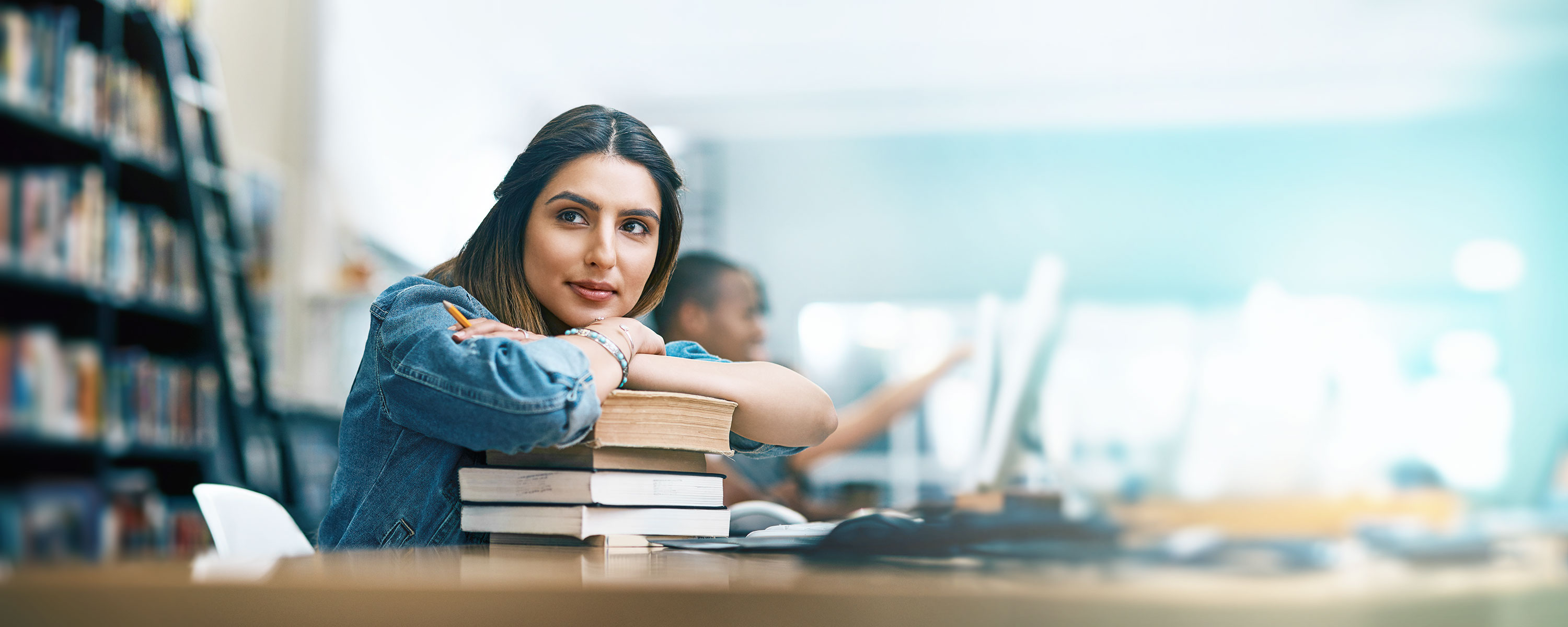 eine Frau sitzt an einem Schreibtisch mit Büchern vor sich (automatisch generiert)